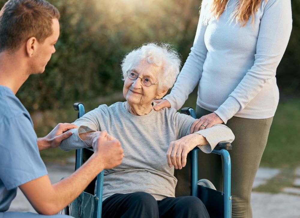 Elderly woman in a wheelchair with a caregiver and a nurse in Houston, TX