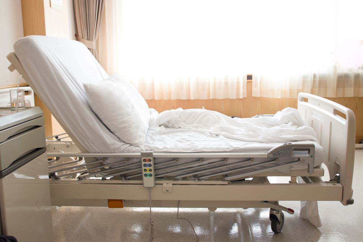 Adjustable hospital bed with white sheets and a remote control in Houston, TX